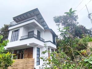 a white house with a black roof at West corner homestay in Shillong