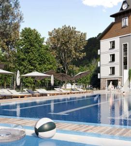 a swimming pool with chairs and umbrellas next to a building at Reef Terrace Apartments in Yaremche