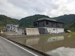 a house on the side of a road next to a body of water at 宜蘭縣三星鄉遇雨魚民宿2932 in Gongzhao