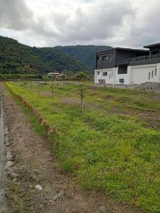 a field of grass with a house in the background at 宜蘭縣三星鄉遇雨魚民宿2932 in Gongzhao