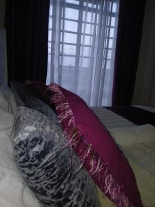 a bed with purple pillows on it with a window at Beijing Nest in Syokimau +3 photos
