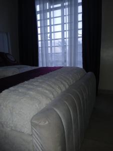 a bedroom with a white bed and a window at Beijing Nest in Syokimau