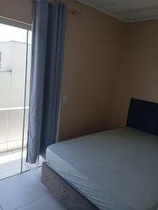 a bedroom with a bed and a window with blue curtains at imovel 2 e 3 in Guaratuba +19 photos