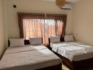 two beds in a room with a window at Sola Hòn Sơn in Lai Sơn