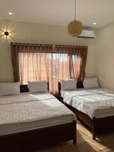 two beds in a room with a window at Sola Hòn Sơn in Lai Sơn