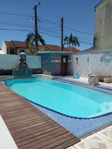 a large blue swimming pool with a wooden deck at imovel 2 e 3 in Guaratuba