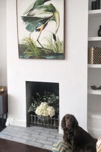 a dog sitting in front of a fireplace with a painting at Beautiful 4 Bed Beach House in Pevensey +27 photos