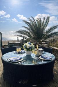 a table with plates and wine glasses on a table on the beach at Beautiful 4 Bed Beach House in Pevensey