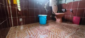 a bathroom with a blue trash can and a toilet at West corner homestay in Shillong