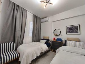 ein Zimmer mit zwei Betten, einem Stuhl und einem Fenster in der Unterkunft Faros in Paphos City