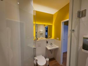 a bathroom with a white toilet and a sink at my MINGA Airport serviced Apartments in Hallbergmoos +24 photos