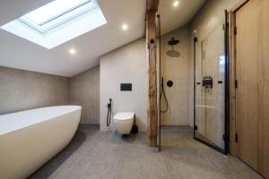 a bathroom with a tub and a toilet and a skylight at Chalet Charm - Private Mountain Retreat with Sauna, Jacuzzi & Kids Playroom in Bansko +42 photos