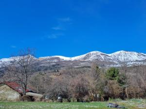 a snow covered mountain range with a house in a field at Le refuge coloré in Gap