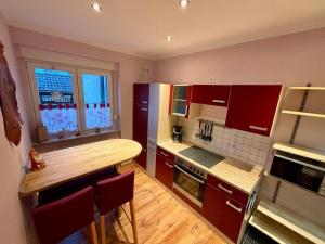 a kitchen with red cabinets and a wooden counter top at Zum Langschläfer in Fredersdorf +4 photos