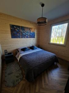 a bedroom with a large bed with a window at Azyl na Polesiu domki przy Poleskim Parku Narodowym in Załucze Nowe