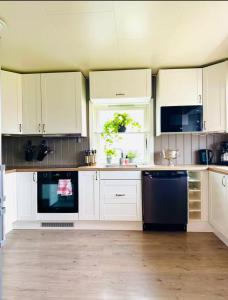 a kitchen with white cabinets and a black dishwasher at Sivi`s hus in Moskenes