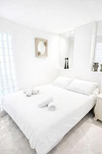 a white bedroom with two beds and a mirror at Le Reflet d'Azur - les pieds dans l'eau in Antibes