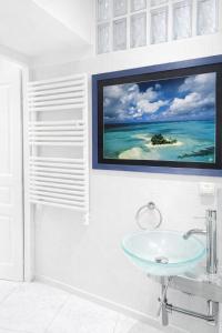 a bathroom with a sink and a tv on the wall at Le Reflet d'Azur - les pieds dans l'eau in Antibes