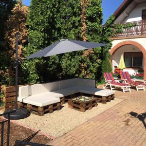 a patio with a couch and an umbrella and chairs at Csuka48 Apartman in Szarvas