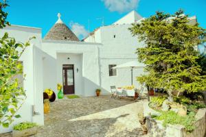 a white house with a table and an umbrella at Il trullo di Memarì in La Correggia