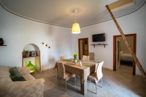 a dining room with a table and chairs and a couch at Il trullo di Memarì in La Correggia