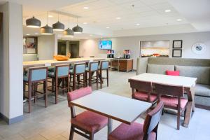 a restaurant with tables and chairs and a bar at Hampton Inn Lima in Lima