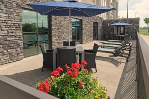 a table and chairs with a blue umbrella and flowers at Hampton Inn Lima in Lima