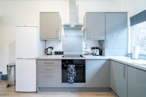 a white kitchen with a stove and a refrigerator at Spacious 3BR Stay - Free Parking - Near City Centre - Sleeps 6 in Manchester