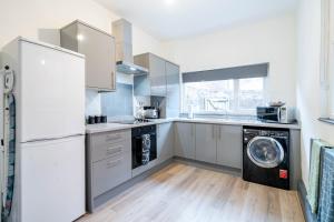 a kitchen with a refrigerator and a washer and dryer at Spacious 3BR Stay - Free Parking - Near City Centre - Sleeps 6 in Manchester