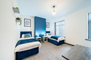 two beds in a room with blue walls at Spacious 3BR Stay - Free Parking - Near City Centre - Sleeps 6 in Manchester