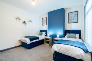 two beds in a room with blue walls at Spacious 3BR Stay - Free Parking - Near City Centre - Sleeps 6 in Manchester +29 photos