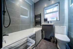 a bathroom with a tub and a toilet and a sink at Spacious 3BR Stay - Free Parking - Near City Centre - Sleeps 6 in Manchester