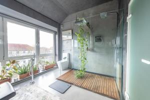 a bathroom with a shower with a plant in it at Stylish Loft Apartment with Designer Bathroom & Balcony in Berlin