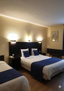 a hotel room with two beds with blue sheets at Hôtel Restaurant Aux Deux Roses in Neuf-Brisach