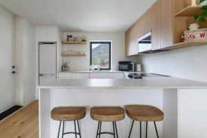 a kitchen with a white counter and stools at Spacious 2BR Retreat, Scenic Views, Modern & New in Whistler