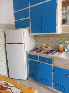 a kitchen with blue cabinets and a white refrigerator at THALIA'S GARDEN in Mytilene