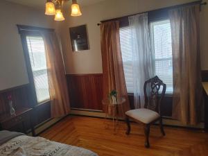 a bedroom with a chair and a bed and windows at Nigam's Sweet Home in Saint John