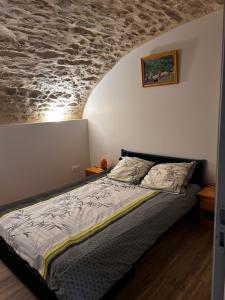 a bed in a bedroom with a stone wall at La Terrette in Vagnas