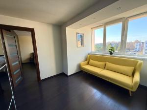 a yellow couch in a room with windows at Birštonas Relax Apartment in Birštonas