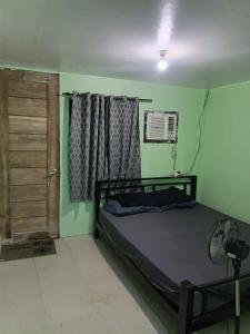 a bedroom with a bed and a window and a fan at Green Pod 2 - Surigao City in Surigao