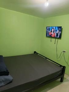a bedroom with a bed with a tv on the wall at Green Pod 2 - Surigao City in Surigao