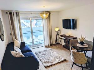 a living room with a blue couch and a tv at Neptune 27 in Swansea