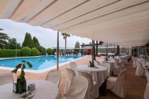 a restaurant with white tables and chairs and a swimming pool at Hotel Restaurant Sol i Vi in Lavern