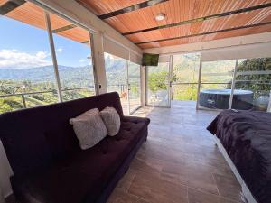 a living room with a couch and a large window at Altavista Tinyhouse in Macanal