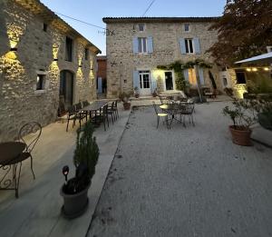 a patio with tables and chairs and a building at La Bastide de Vallon in Vallon-Pont-dʼArc