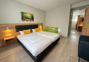 a bedroom with a large white bed with yellow pillows at Hotel Gute Hoffnung Pforzheim in Pforzheim