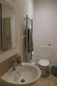 a white bathroom with a sink and a toilet at Stunning Seafront Apartment in Aberystwyth