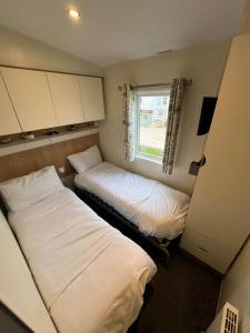 two beds in a small room with a window at Towyn Happy Days S7 in Rowen