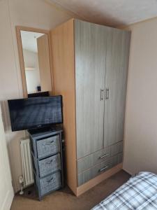 a bedroom with a large cabinet and a bed at Buttercup Retreat 298 northfield in Skipsea