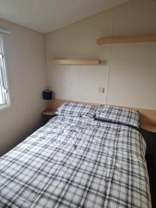 a bed in a room with a plaid blanket on it at Buttercup Retreat 298 northfield in Skipsea